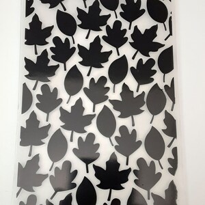 May include: A clear plastic sheet with a repeating pattern of black leaf shapes. The leaves are in various sizes and shapes, including maple, oak, and simple oval leaves.