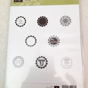 Può includere: Un set di otto timbri trasparenti con vari disegni, tra cui "You make me smile", "Be mine", "For you", "Thank U" e "T is for kindness". I timbri sono disposti in una griglia su uno sfondo bianco. Il titolo "A Round Array" è stampato nella parte superiore del foglio.