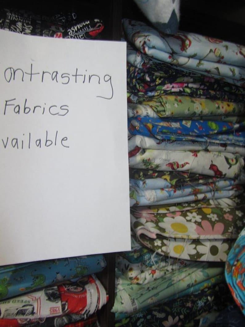 May include: A stack of colorful fabric scraps with a handwritten sign that reads "Contrasting Fabrics Available".