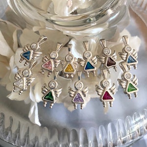 May include: A collection of silver angel charms with different colored gemstones. The charms feature a small angel with wings and a gemstone in the center. The gemstones are pink, yellow, blue, purple, green, and red.