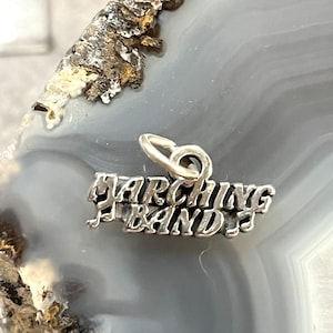 May include: Silver charm with the words "Marching Band" in a stylized font.