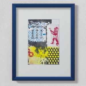 May include: Abstract art print in a blue frame. The artwork features a collage of colors and shapes, including blue dots, yellow and black patterns, and a red figure holding a tool. The print is mounted on a white background.