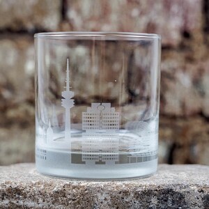 May include: A clear glass tumbler with a frosted cityscape design. The cityscape features a tall tower and other buildings.
