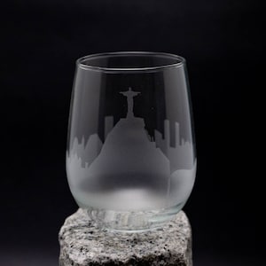 May include: A clear glass wine glass with an etched design of the Christ the Redeemer statue and the Rio de Janeiro skyline.