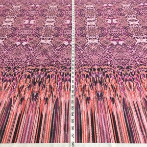 May include: A pink and orange fabric with a snake skin pattern. The fabric is measured with a tape measure that shows 60 inches.