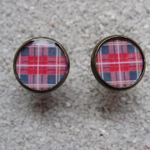 Puede incluir: Un par de pendientes con un patrón de cuadros rojos, blancos y azules. Los pendientes están hechos de metal y tienen una forma redonda.