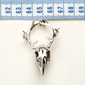 May include: Silver pendant featuring a detailed skull with antlers. The pendant is approximately 2 inches in length.