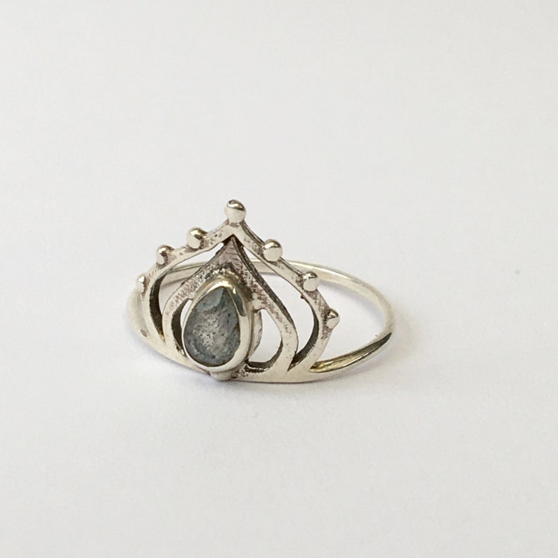 May include: A silver ring with a teardrop-shaped gemstone set in a crown design.