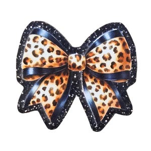 May include: A decorative bow with a leopard print pattern. The bow features a black glitter outline and a black satin ribbon. The bow's center knot is also leopard print.