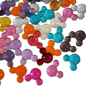 May include: Assortment of colorful, sparkly, rhinestone Mickey Mouse ears. The ears are in various colors, including red, blue, green, purple, orange, and pink.