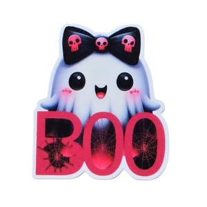 May include: A Halloween-themed sticker featuring a cartoon ghost with a black bow adorned with skull accents. The ghost is holding the word "BOO" in red, with spiderweb details. The ghost has rosy cheeks and a happy expression.