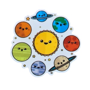 May include: A die-cut sticker featuring a central yellow sun surrounded by seven colorful planets, each with a simple cartoon face. The planets include shades of orange, green, blue, and beige, with two planets featuring rings. Small yellow stars and dots are scattered throughout.