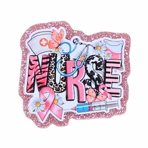 May include: A pink glittery badge with the word "NURSE" in a mix of patterns and colors. The design includes a nurse's hat, stethoscope, flowers, butterflies, a syringe, and a pink ribbon.