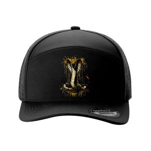 May include: Black baseball cap with a gold cobra design. The cobra is detailed with a dripping effect. The cap has a curved peak and a snapback closure. Other cap colours are shown, including red, grey, and navy.