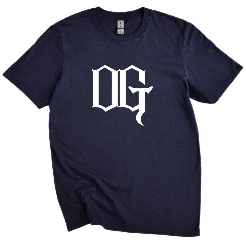 May include: Navy blue t-shirt with the white letters "OG" in a stylized font. The short-sleeved shirt is made of a soft material and is suitable for casual wear.