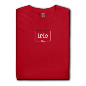 May include: A folded red t-shirt with the word "irie" in a white rectangular box, with "Yard" below it. The shirt is part of a collection of various colored t-shirts.