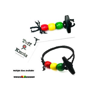 May include: A black bracelet and a beaded toggle clasp, featuring red, yellow, and green beads. The image also shows a matching toggle clasp and a tag that reads "Tuff & Knots".