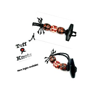 May include: Two handmade wooden toggle bracelets. The bracelets feature a series of patterned beads in red, white, and black, connected by black cord. The toggle is black. The image includes a tag with the text "Tuff Knots" and "More Styles Available!"