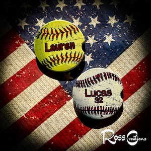 May include: Two baseball-themed car coasters. One is yellow with "Lauren" in red, the other is white with "Lucas 32" in red. Both have red stitching and are set against a distressed American flag background.