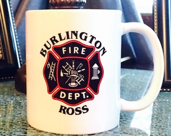 May include: White ceramic coffee mug with a black and red fire department logo. The logo says "Burlington Fire Dept. Ross" with a firefighter's helmet, axe, ladder, and fire hydrant.