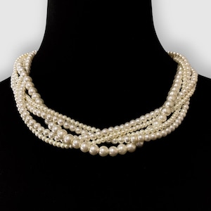 May include: A multi-strand pearl necklace with a classic design. The necklace is made of white pearls and is arranged in a layered pattern.