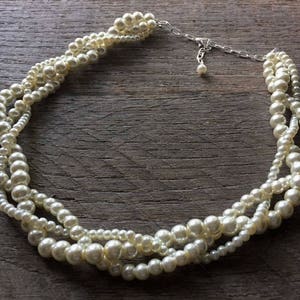 May include: A multi-strand pearl necklace with a silver clasp. The pearls are white and have a slight iridescent sheen.
