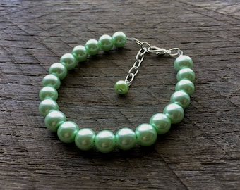 May include: A green pearl bracelet with a silver clasp. The bracelet is made of round pearls and is approximately 18 inches in length.