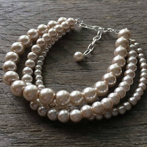 May include: A multi-strand pearl necklace with a silver clasp. The pearls are cream colored and have a slight iridescent sheen.