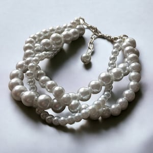 May include: A white pearl necklace with multiple strands and a silver clasp.