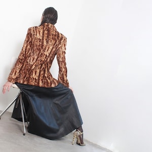 May include: A brown and tan patterned blazer with a black leather skirt and gold heels.