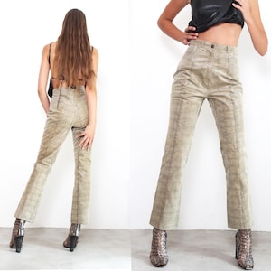 Może przedstawiać: Beżowe spodnie sztruksowe z subtelnym wzorem w kratę. Spodnie mają wysoki stan i rozszerzaną nogawkę. Modelka ma na sobie spodnie z czarnym topem i wzorzystymi butami. Spodnie są w stylu vintage.