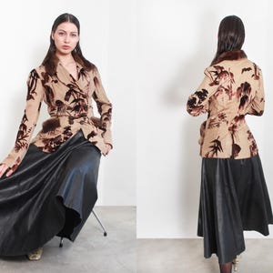 Peut inclure: Un blazer beige à motifs floraux et garniture en fourrure, associé à une longue jupe noire. Le blazer présente une conception enveloppante et des manches longues. La jupe a une silhouette fluide, créant une esthétique vintage.