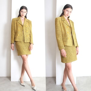 May include: A yellow tweed skirt suit with a double-breasted jacket and a short skirt.
