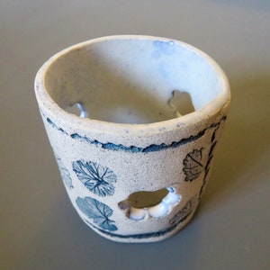 May include: White ceramic planter with a blue and white leaf design and cut-out holes.
