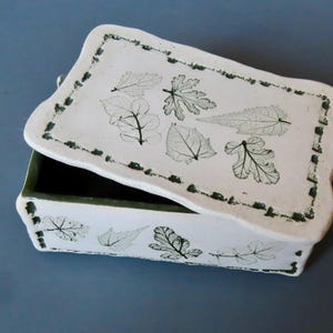 Caja de cerámica rectangular hecha a mano de gres con hojas verdes impresas, tapa y interior esmaltado en verde. Hojas reales utilizadas para crear impresiones.
