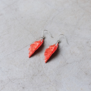 May include: A pair of dangle earrings featuring a red leaf design. The leaves are textured and have a metallic sheen.
