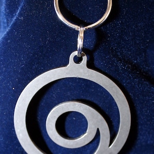 May include: A silver metal keychain with a spiral design. The keychain is attached to a silver ring.