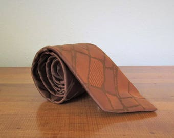 May include: A brown patterned silk tie rolled up. The pattern is a geometric design of brown and tan squares.