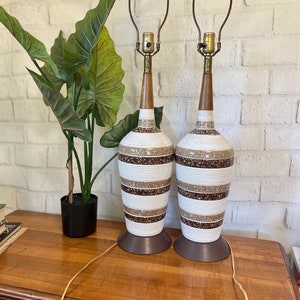 May include: A pair of vintage ceramic table lamps with brown and white striped designs. The lamps have a wooden base and a brass harp.