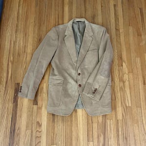 May include: A beige corduroy blazer with a single-breasted closure and two front pockets.