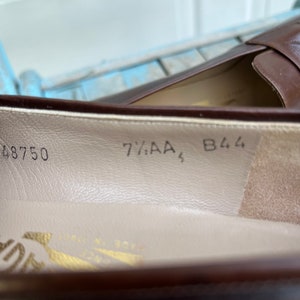 May include: Close-up of the inside of a brown leather shoe with the size 7 1/2 AA, 48750, and B44 printed on the insole.