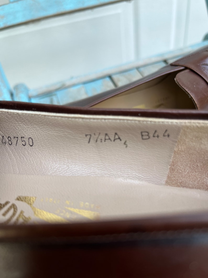 May include: Close-up of the inside of a brown leather shoe with the size 7 1/2 AA, 48750, and B44 printed on the insole.