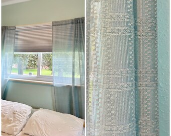 Könnte beinhalten: Ein Schlafzimmer mit einem Bett, weißen Kissen und einem Fenster mit hellblauen Vorhängen. Die Vorhänge haben ein weißes Muster und sind durchsichtig.