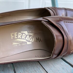 May include: Brown leather loafers with a gold embossed "Salvatore Ferragamo" logo on the insole. The loafers are made in Italy and have a size 8.5 printed on the insole.