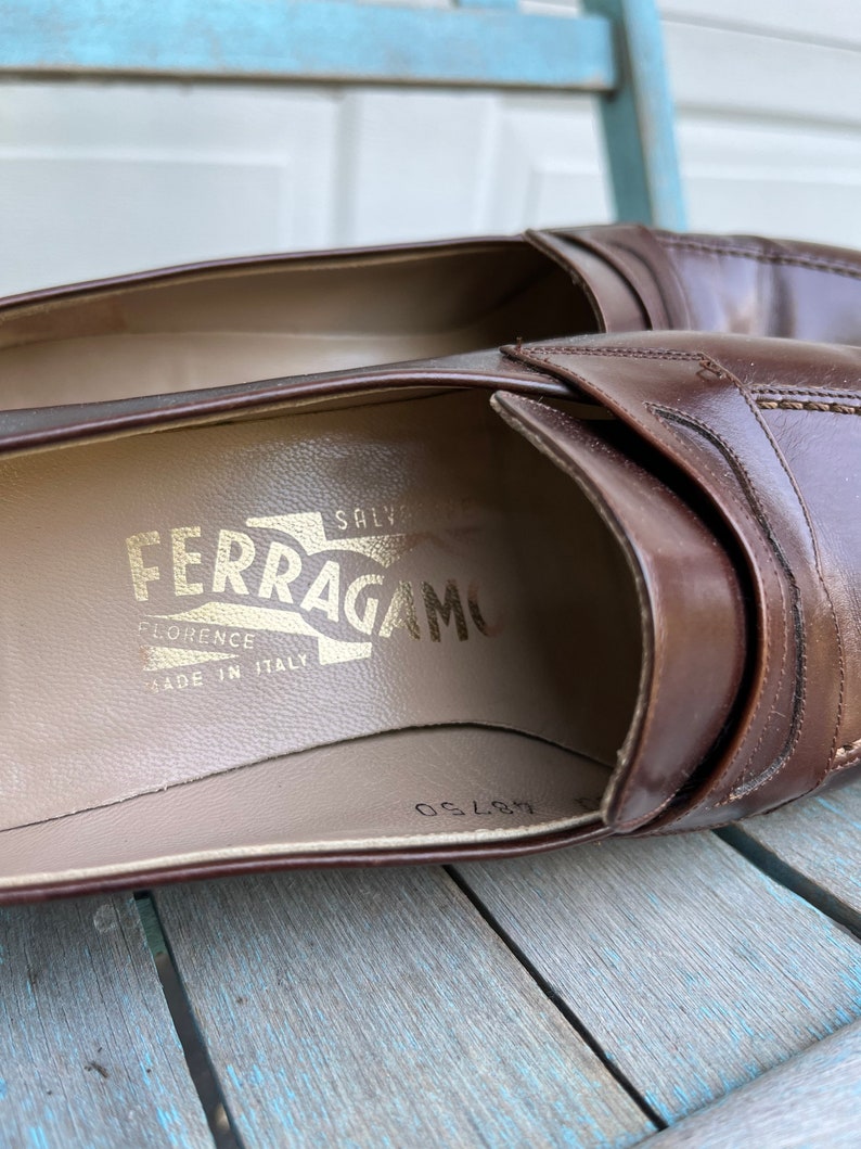 May include: Brown leather loafers with a gold embossed "Salvatore Ferragamo" logo on the insole. The loafers are made in Italy and have a size 8.5 printed on the insole.