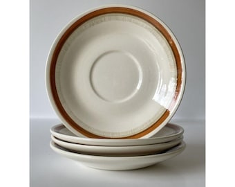May include: Set of four white ceramic saucers with a brown and orange stripe design.