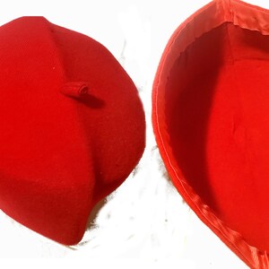May include: A red beret with a small loop on the top. The beret is shown from both the outside and inside.