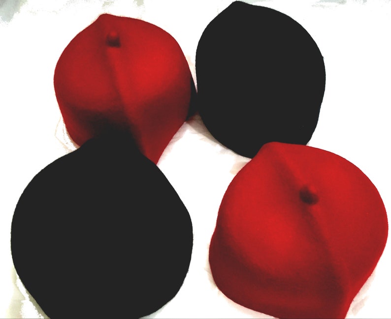 May include: Four felt hats, two red and two black, arranged in a circle on a white surface.
