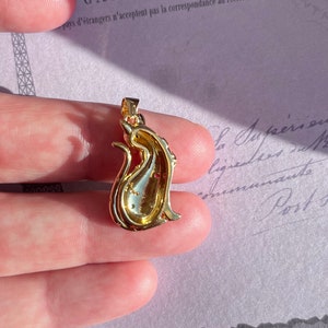 May include: Gold-tone pendant featuring a detailed cat design with red rhinestones. The pendant is shown from the back, revealing the intricate details of the design.