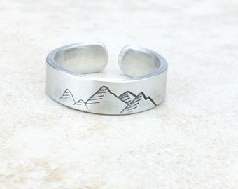 Puede incluir: Un anillo de plata con un diseño de cordillera grabado en la banda.